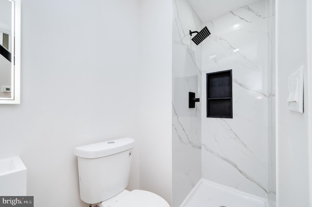 bathroom with tiled shower and toilet