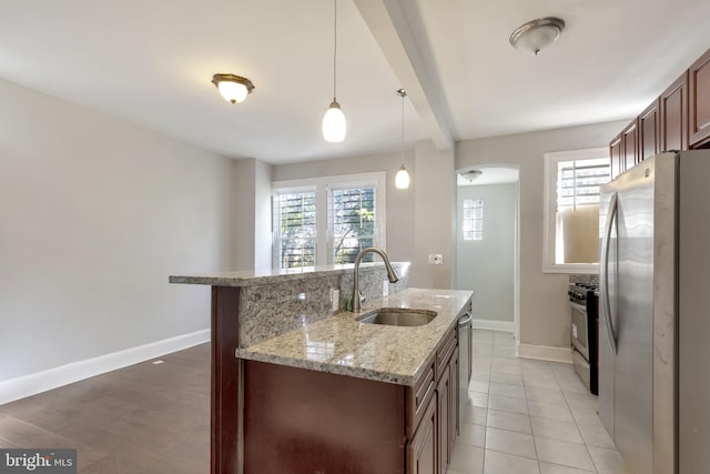 kitchen featuring hanging light fixtures, a wealth of natural light, fridge, and sink