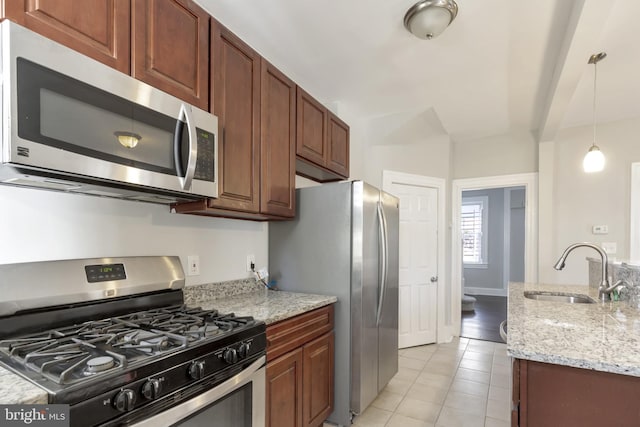 kitchen featuring appliances with stainless steel finishes, decorative light fixtures, light stone counters, and sink