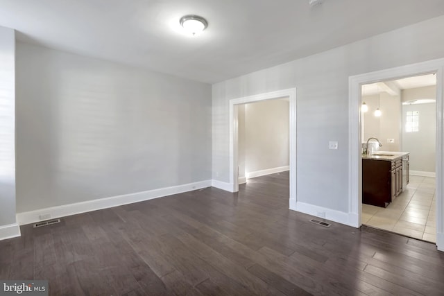 spare room with sink and dark wood-type flooring