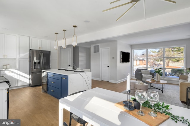 kitchen with decorative light fixtures, white cabinetry, tasteful backsplash, stainless steel fridge, and blue cabinets