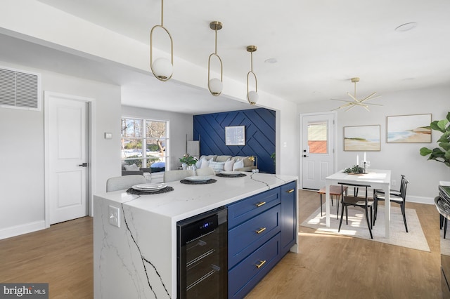 kitchen featuring decorative light fixtures, light stone counters, dark hardwood / wood-style floors, and wine cooler