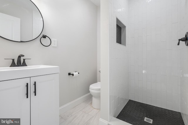 bathroom with toilet, vanity, and tiled shower