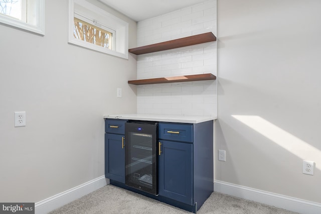 bar with light carpet, backsplash, blue cabinets, and beverage cooler