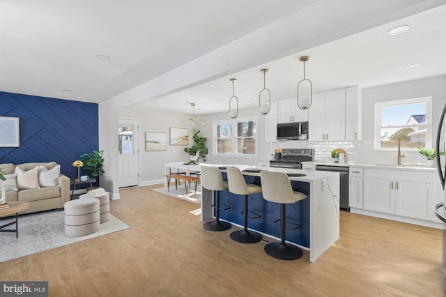 kitchen with a center island, pendant lighting, white cabinetry, a breakfast bar area, and stainless steel appliances