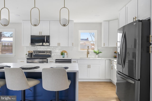 kitchen with decorative light fixtures, stainless steel appliances, and white cabinetry