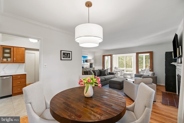 dining area featuring light tile patterned floors, a fireplace, and crown molding