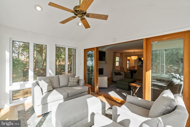 sunroom / solarium featuring plenty of natural light, a fireplace, vaulted ceiling, and a ceiling fan