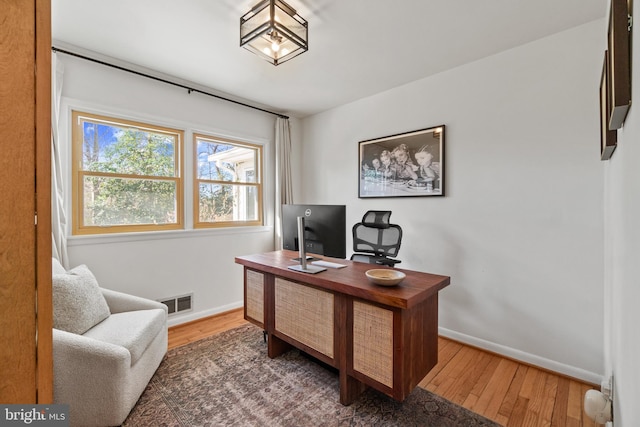 office area featuring wood-type flooring, visible vents, and baseboards