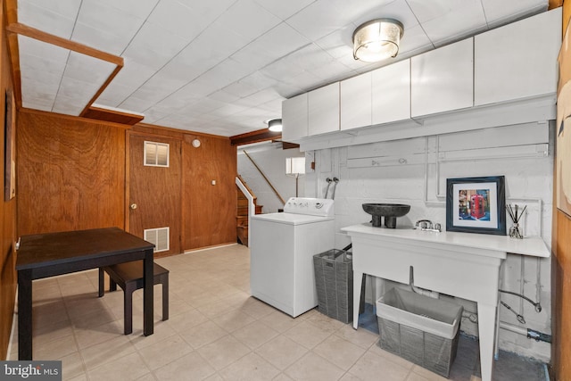 clothes washing area with visible vents, washer / clothes dryer, wood walls, and cabinet space