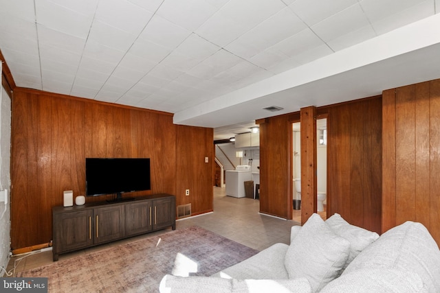 living room with washer / dryer, wooden walls, visible vents, tile patterned floors, and stairs