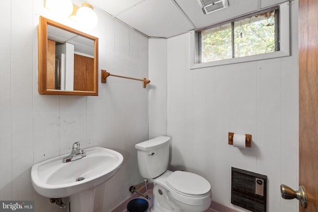 bathroom featuring heating unit, visible vents, toilet, and a sink