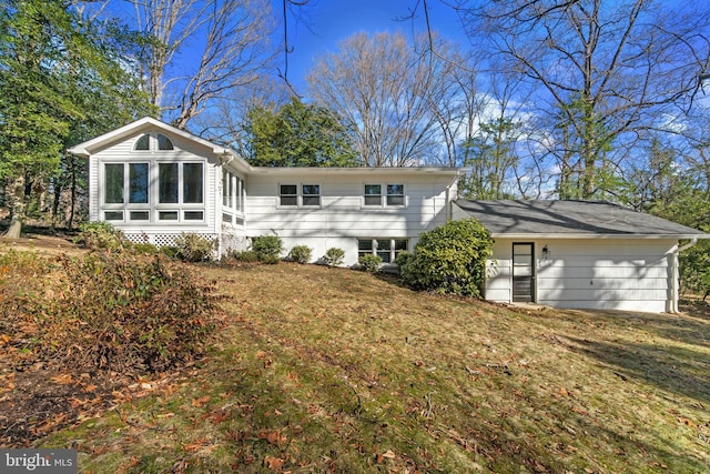 back of house featuring an attached garage, a sunroom, and a yard