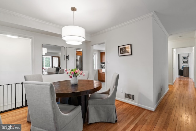 dining room with light wood-style floors, visible vents, ornamental molding, and baseboards