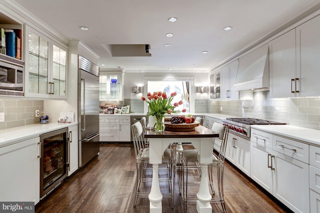 kitchen featuring premium range hood, beverage cooler, white cabinets, and built in appliances