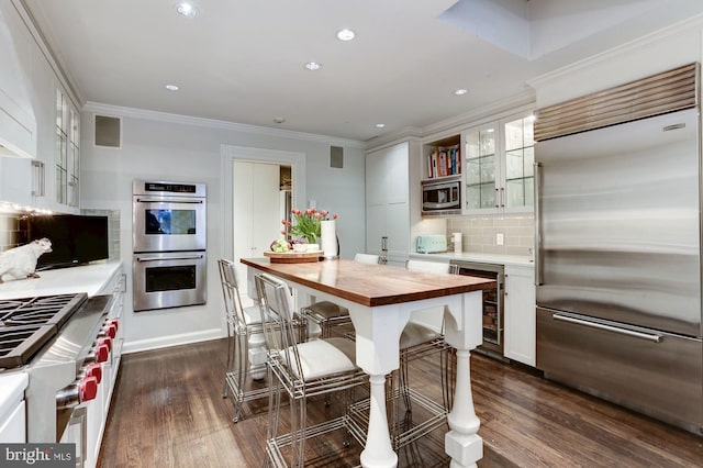 kitchen with backsplash, white cabinetry, built in appliances, and wine cooler