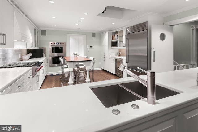 kitchen featuring crown molding, white cabinets, dark hardwood / wood-style flooring, and built in appliances