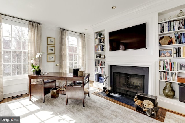 office space featuring built in shelves, crown molding, and hardwood / wood-style floors