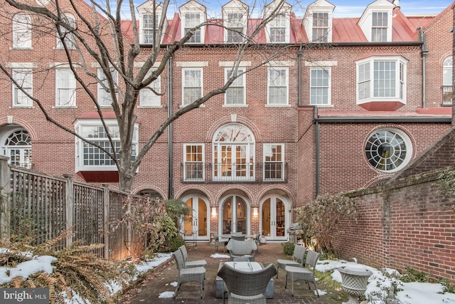 snow covered rear of property featuring a patio area