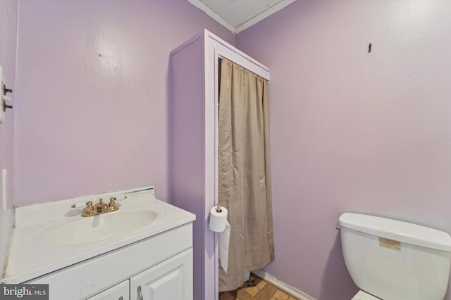 bathroom with toilet, vanity, and ornamental molding