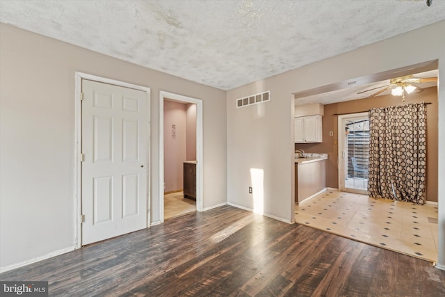 unfurnished living room with a textured ceiling, ceiling fan, and dark hardwood / wood-style flooring