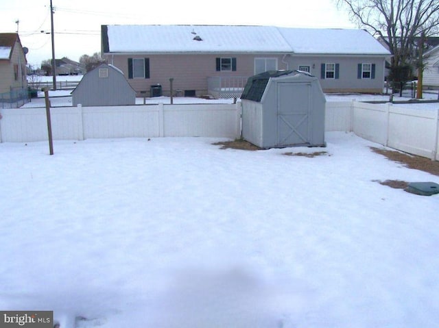 snowy yard featuring a storage shed and central air condition unit