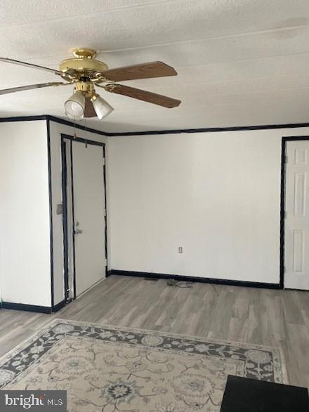 unfurnished room featuring a textured ceiling, ceiling fan, hardwood / wood-style flooring, and crown molding