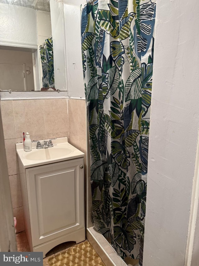 bathroom featuring backsplash, vanity, tile walls, and walk in shower