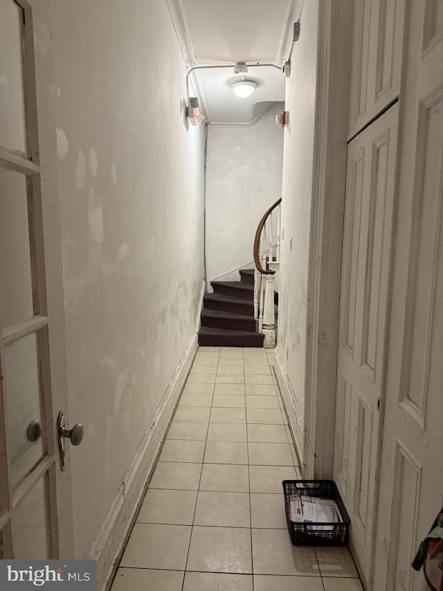 corridor with ornamental molding and light tile patterned flooring