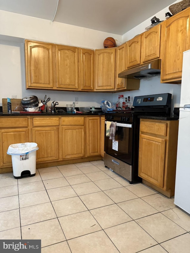 kitchen featuring gas range oven, light tile patterned floors, white refrigerator, and sink