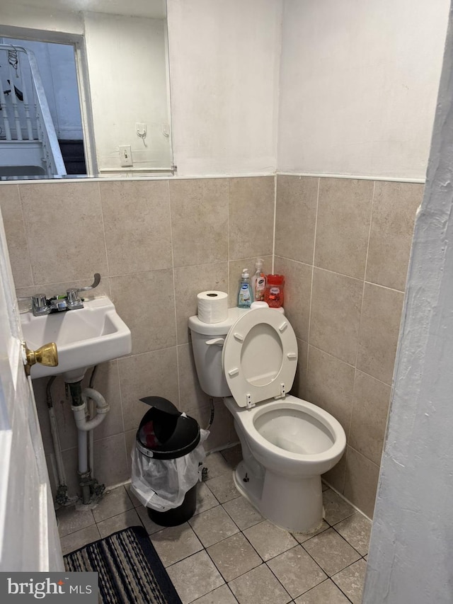 bathroom with sink, tile patterned flooring, tile walls, and toilet