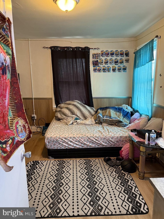 bedroom with hardwood / wood-style floors and wooden walls