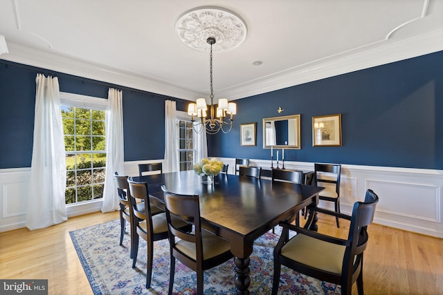 dining area featuring an inviting chandelier, crown molding, and light wood-type flooring