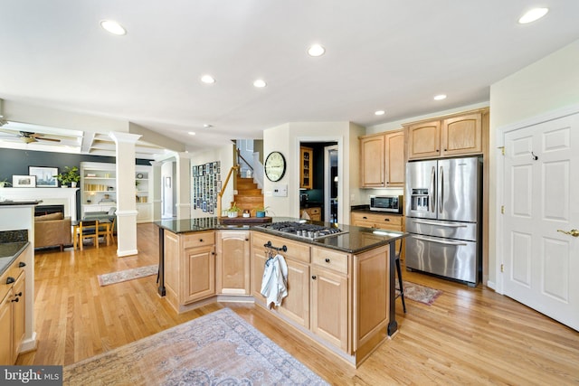 kitchen featuring a kitchen island, dark stone countertops, a breakfast bar area, stainless steel appliances, and light wood-type flooring