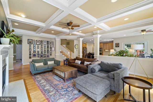 living room with decorative columns, coffered ceiling, light wood-type flooring, and beam ceiling