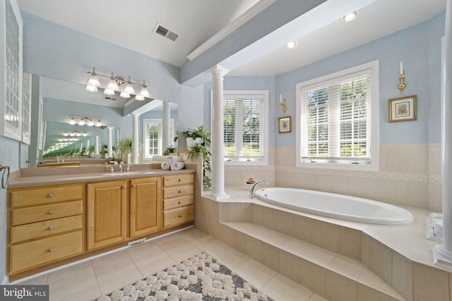 bathroom featuring vanity, tile patterned flooring, decorative columns, and a relaxing tiled tub