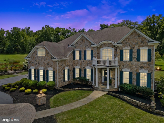 colonial-style house featuring a balcony and a lawn