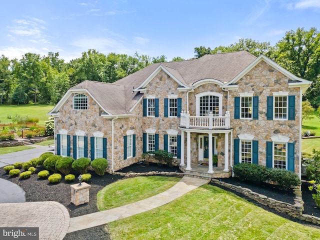 colonial home featuring a front yard and a balcony