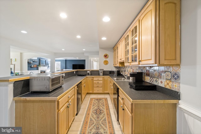 kitchen featuring light tile patterned floors, dishwasher, backsplash, light brown cabinetry, and kitchen peninsula