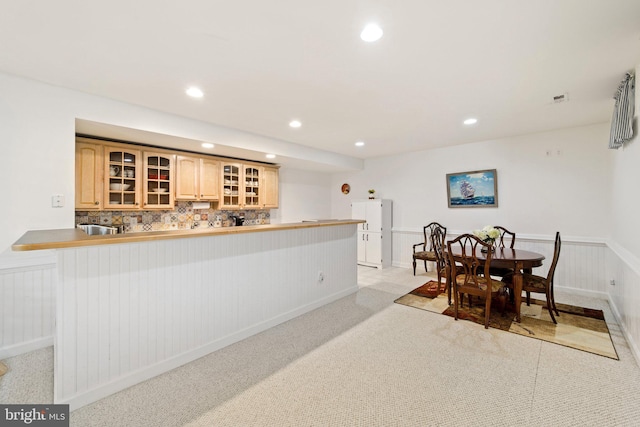 kitchen with tasteful backsplash, light carpet, light brown cabinets, and kitchen peninsula