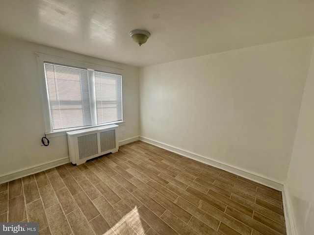 spare room with hardwood / wood-style floors and radiator heating unit