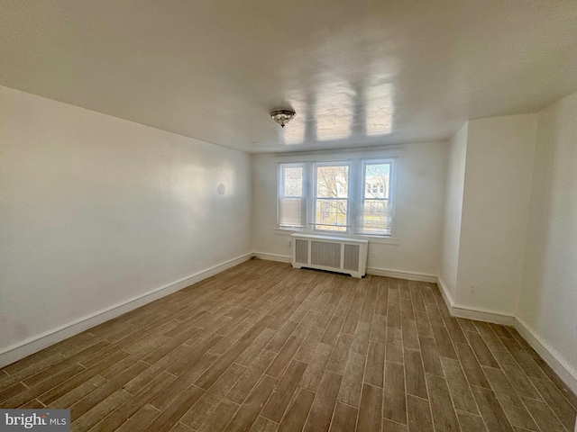 spare room with radiator heating unit and wood-type flooring