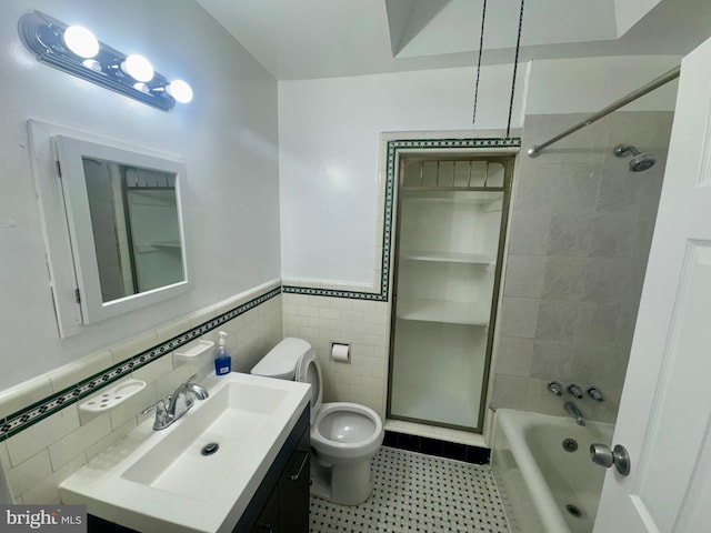 full bathroom featuring tiled shower / bath, vanity, tile walls, and toilet