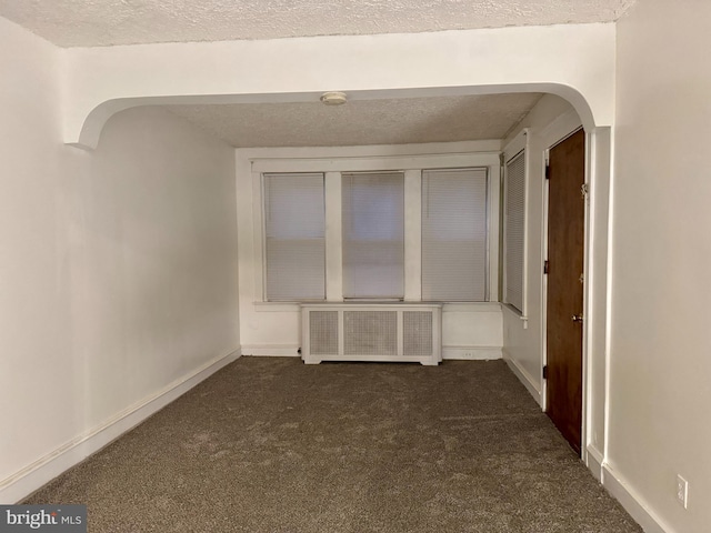 carpeted spare room with radiator and a textured ceiling