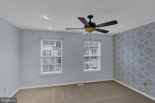 unfurnished room featuring a healthy amount of sunlight, ceiling fan, and carpet