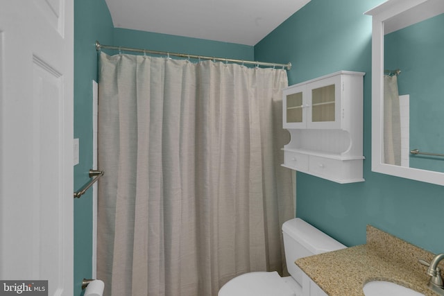 bathroom featuring toilet, a shower with shower curtain, and vanity