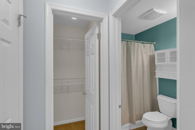 bathroom with a shower with shower curtain and toilet