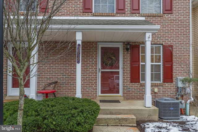 snow covered property entrance with central air condition unit