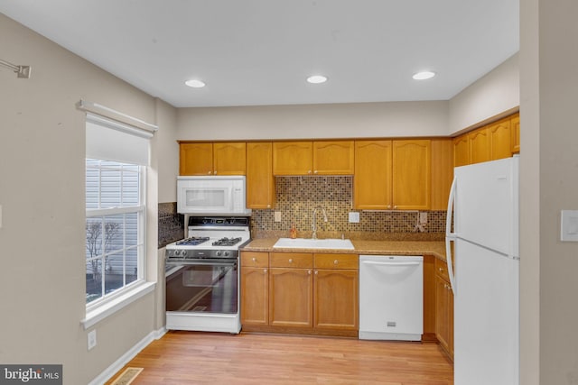 kitchen featuring white appliances, light hardwood / wood-style floors, decorative backsplash, and sink