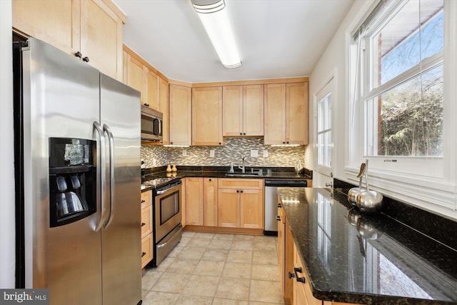 kitchen featuring dark stone counters, stainless steel appliances, light brown cabinetry, and sink